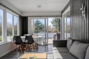 a living room with a table and chairs and windows at 1102-Ringkobing-Gransangervej-14 in Nørby