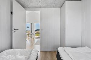 a bedroom with white walls and a bed and a table at 1194-Ringkobing-Havstien-203 in Søndervig