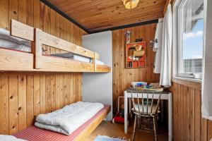 a bedroom with two bunk beds and a table at 1197-Ringkobing-Nordlysvej-17 in Søndervig