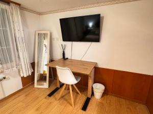 a desk with a chair and a television on a wall at HausHarder Rooms in Gommiswald