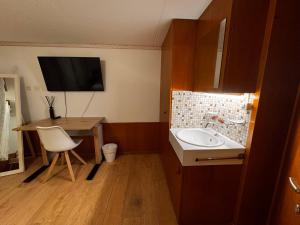a bathroom with a sink and a desk with a television at HausHarder Rooms in Gommiswald