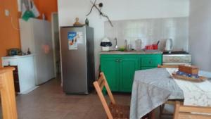 a kitchen with green cabinets and a stainless steel refrigerator at Cabaña Tupa mba'e, En el Ibera in San Miguel