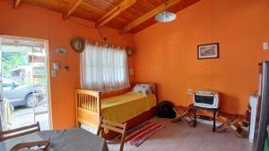a bedroom with orange walls and a bed and a desk at Cabaña Tupa mba'e, En el Ibera in San Miguel