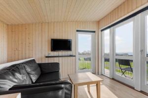 a living room with a black leather couch and a tv at FY293-Faaborg-Mosegarden-42 in Faaborg