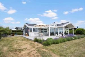 a white house with an umbrella and a yard at FY261-Ebberup-Hasselvaenget-22 in Ebberup