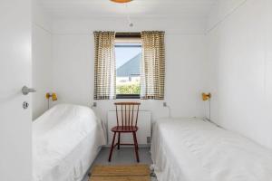 a bedroom with two beds and a chair and a window at FY184-Asperup-Eskelundsvej-21 in Asperup