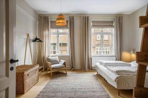a bedroom with a bed and a chair and windows at FY399-Bogense-Ostergade-5-a in Bogense