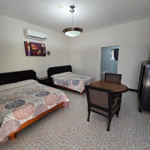 a room with two beds and a table and a desk at Hotel Catalina in Torreón