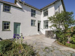 a white house with a green door and flowers at Ty Mawr Farm in Llanfairpwllgwyngyll