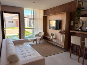 a living room with a white couch and a tv at Chalé de Luxo com Piscina em Barra dos Coqueiros, Sergipe in Barra dos Coqueiros