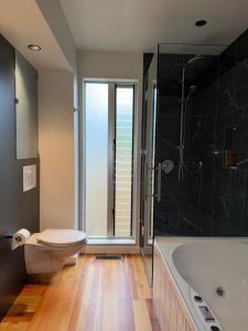a bathroom with a toilet and a bath tub at Raumati Sunsets in Raumati Beach