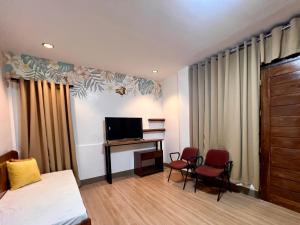 a room with a bed and a television and a desk at OHANA Homestay in Coron