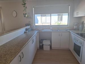 a kitchen with white cabinets and a sink and a window at Moto GP Hidden Gem in Coronet Bay +4 photos