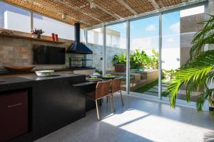 a kitchen with a island with a table and chairs at Chalé de Luxo com Piscina em Barra dos Coqueiros, Sergipe in Barra dos Coqueiros