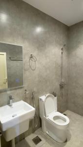 ein Badezimmer mit weißer Toilette und Waschbecken in der Unterkunft Alturya in Al-'Ula