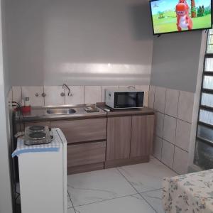 a small kitchen with a microwave and a sink at Small and cozy in Ijuí