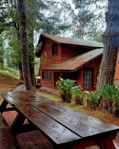 a wooden picnic table in front of a log cabin at Cabañas El Rincón de Pancho in Altotonga +17 photos