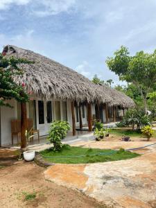 a house with a straw roof with a yard at Sunset Rote Bungalows in Nembrala