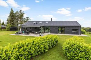 a house with a black roof on a yard at 8912-Allingabro-Fyrrevej-6 in Allingåbro