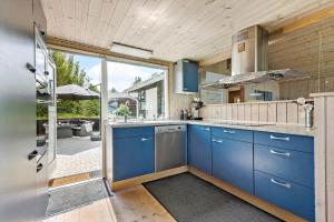 a large kitchen with blue cabinets and a patio at 8903-Allingabro-Fyrrevej-12 in Allingåbro +18 photos