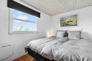 a white bedroom with a bed and a window at 8903-Allingabro-Fyrrevej-12 in Allingåbro