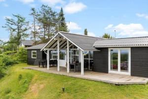 a small house with a deck and a patio at 8903-Allingabro-Fyrrevej-12 in Allingåbro