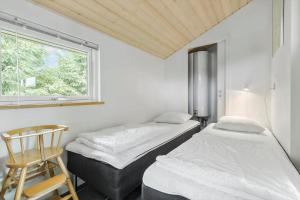 two beds in a room with a chair and a window at 8920-Orsted-Ternevej-16 in Ørsted