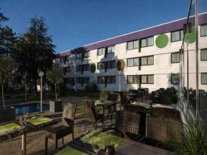 a hotel with tables and chairs in front of a building at Sunday Saarbruecken Sued Standard Room in Saarbrücken