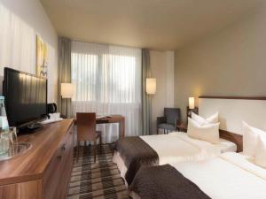 a hotel room with a bed and a desk with a television at Sunday Saarbruecken Sued Standard Room in Saarbrücken
