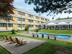 a building with chairs and a pool in front of it at Sunday Saarbruecken Sued Standard Room in Saarbrücken