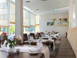 a dining room with tables and chairs and windows at Sunday Saarbruecken Sued Standard Room in Saarbrücken