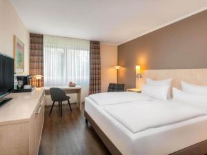 a hotel room with a large white bed and a desk at Sunday Hotel Bielefeld Standard King Room in Bielefeld +28 photos