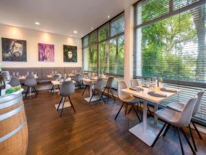 a restaurant with tables and chairs and large windows at Sunday Hotel Bielefeld Standard King Room in Bielefeld