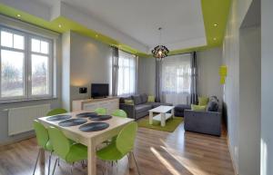 uma sala de estar com uma mesa e cadeiras verdes em Apartament Glamour DeLux 53m - blisko szlaków em Karpacz