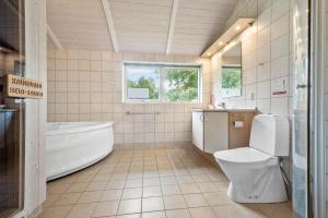 a bathroom with a tub and a toilet and a sink at 8519-Grenaa-Nobilisvej-13 in Grenå