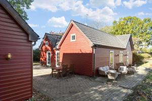 a red barn with a patio in front of a house at 8514-Grenaa-Sortebaervej-16 in Grenå