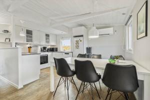 a white kitchen with black chairs and a table at 8963-Orsted-Spovevej-6 in Ørsted +17 photos