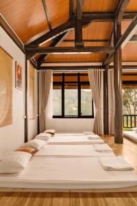 a large white bed in a room with windows at Trám House in Cao Phong +42 photos