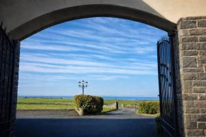 an archway leading to a gate with a field behind it at Aran View Holiday Homes Doolin - The Courtyard House - Sleeps 9 in Knockfin Cross Roads