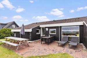 a patio with a picnic table and chairs and a house at 8927-Allingabro-Nordvangsvej-27 in Allingåbro