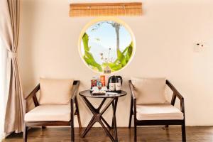 two chairs and a table in a room with a round window at Trám House in Cao Phong