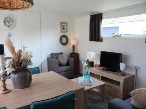 a living room with a table and a television at Charming Chalet in De Rijp in West-Graftdijk +3 photos