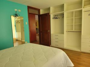 a bedroom with a white bed and green walls at Hospedaje Campestre María Eugenia in Cajamarca