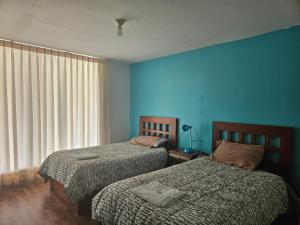 two beds in a room with blue walls at Hospedaje Campestre María Eugenia in Cajamarca