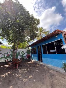 a blue house with a tree and chairs in front of it at Hostel Caiçara in Santo Amaro