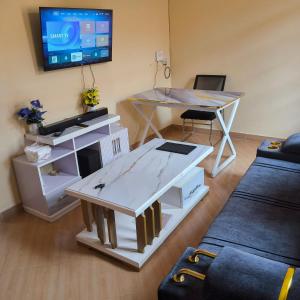 a living room with a table and a tv at Snug Spot BnB-Mwea in Thiba