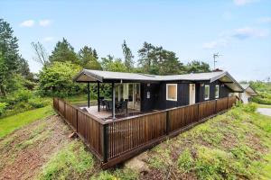 a black house with a deck on a field at 8017-Knebel-Manhojvej-1 in Knebel