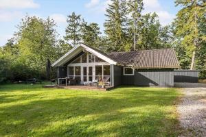 a small black house with a large yard at 84148-Ebeltoft-Sivsangervej-47 in Ebeltoft