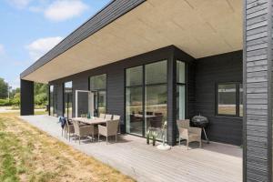 a black house with a deck with a table and chairs at 84160-Ebeltoft-Baekholmen-5-A in Ebeltoft