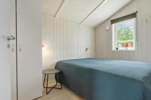 a bedroom with a blue bed and a window at 8014-Knebel-Rastestedet-16 in Knebel